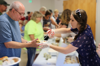 Woman serving food to a elderly man